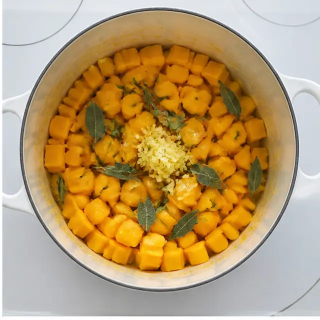Step 2: Adding butternut squash cubes, fresh herbs, garlic, and ginger to the pot