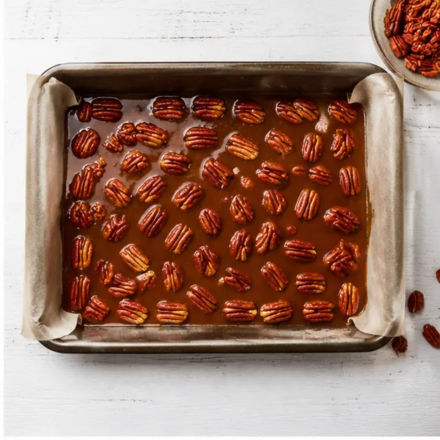 Pour the caramel glaze into a parchment-lined 9x13 baking pan and scatter pecan halves evenly over the top
