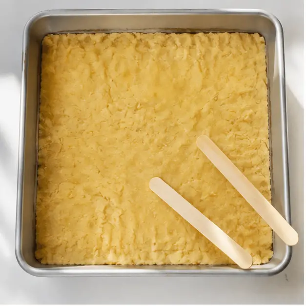 Pressing the buttery cake mix crust evenly into the 9x13 pan