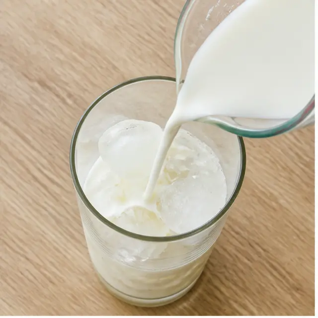 Fill the tall glass with ice and pour cold milk over the cubes, listening for the crackle.