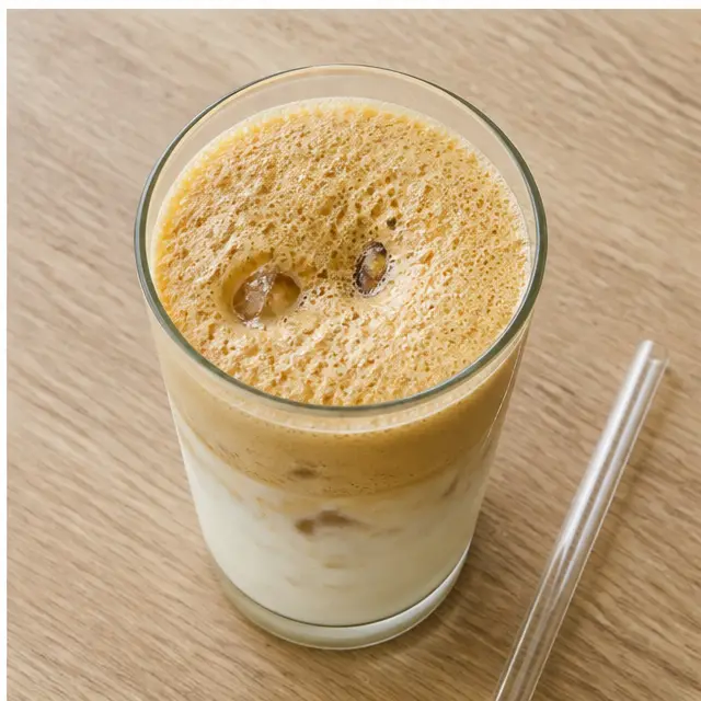 Pour the foamy espresso mixture over the milk and ice, then stir gently and serve immediately.