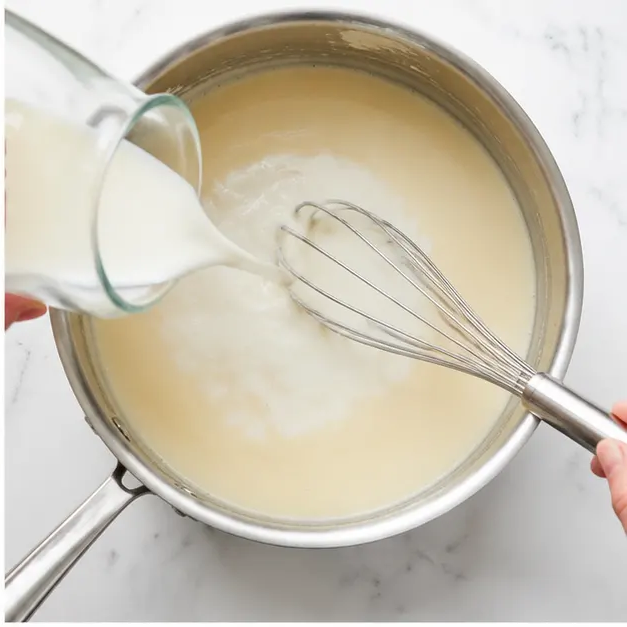 Step 2: Pouring milk to create a smooth sauce