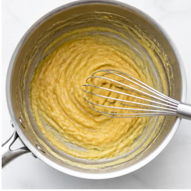 Whisking all-purpose flour into melted butter to make a golden roux