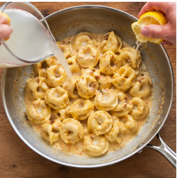Step 3: Tossing the drained tortellini with bloomed Cajun spices, smoked paprika, pasta water and Meyer lemon